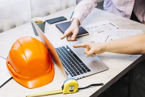 Casco de obra, planos y ordenador sobre una mesa de trabajo